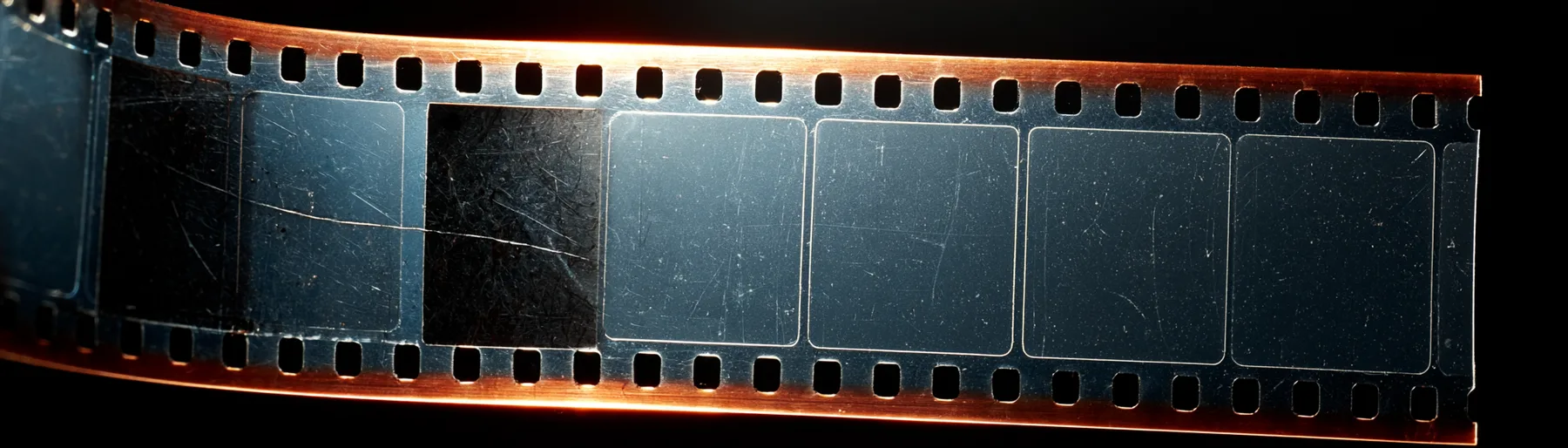 Pás filmu proti světlu. Mezi exponovanými políčky jsou zcela prázdná, čirá políčka.